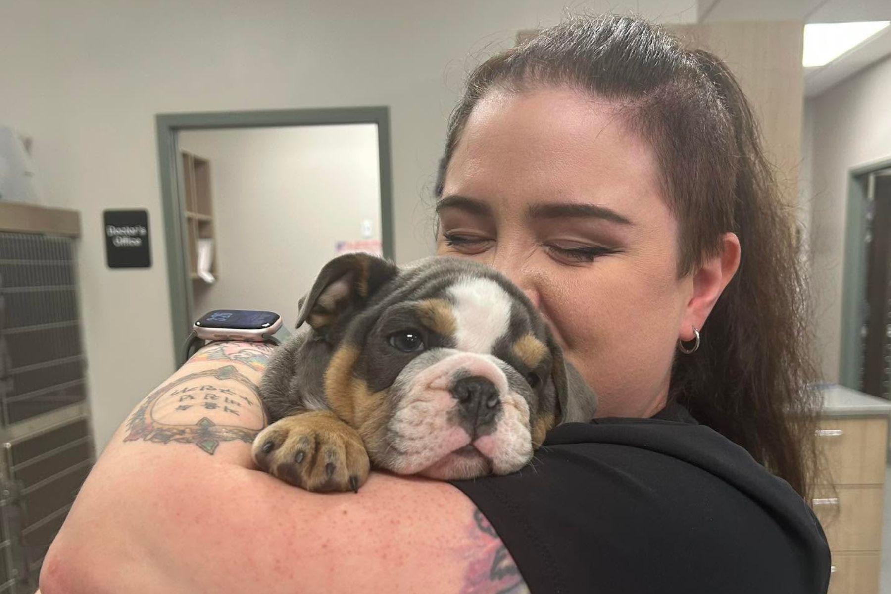 A woman gently cradles a bulldog puppy in her arms